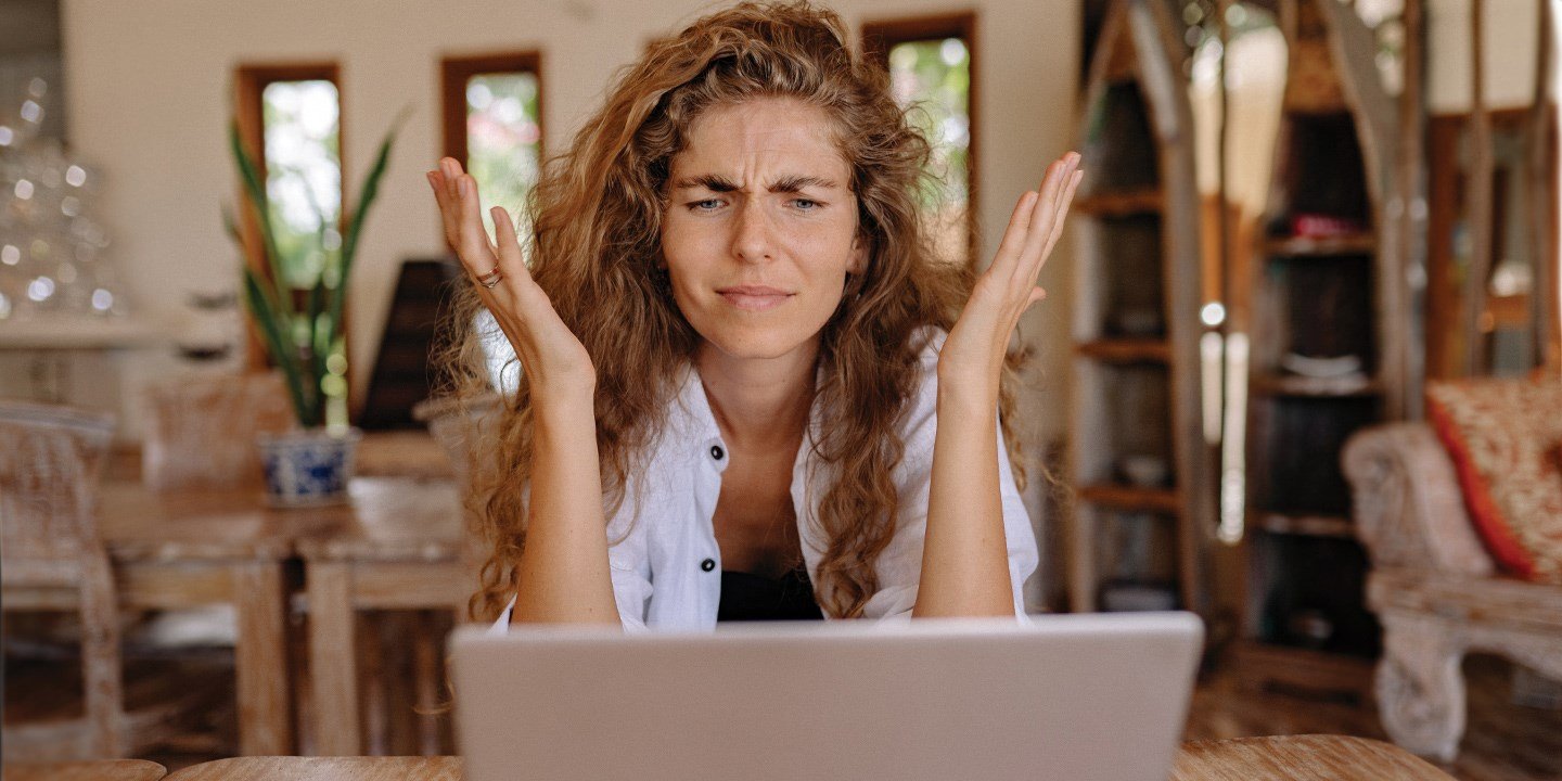 Woman holding up her hands in confusion in front of her laptop