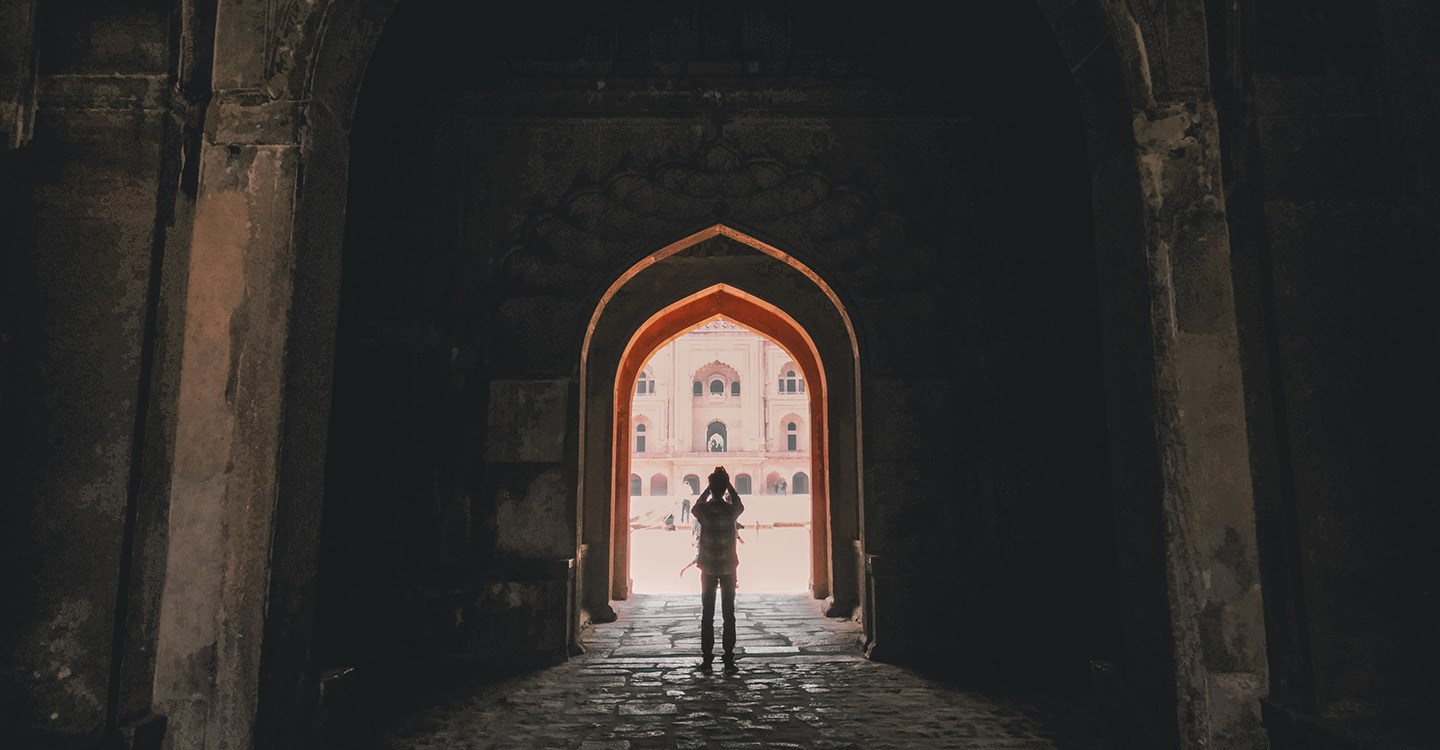 Person standing in large building archway to take a photo