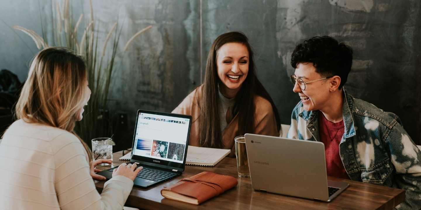 three friends laughing and planning in a cafe