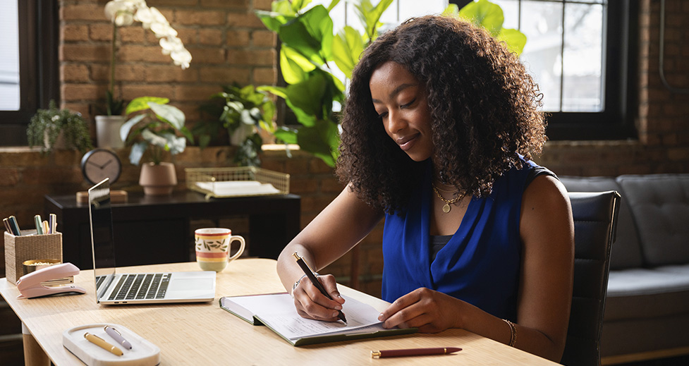 Woman working at her desk and writing plans in her FOUNDATION Planner.