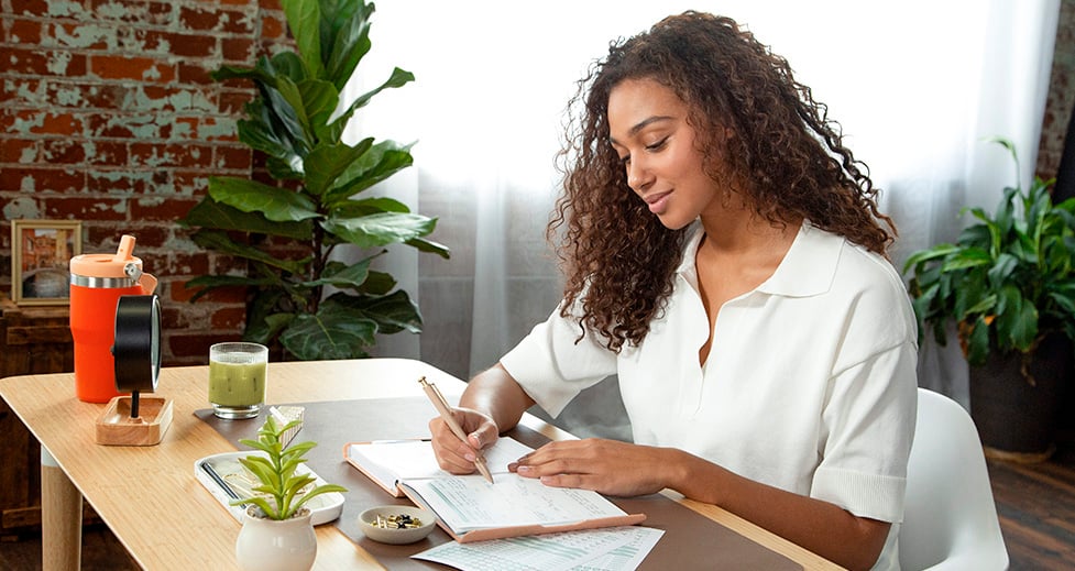 Woman working at her desk and writing plans in her FOUNDATION Planner.