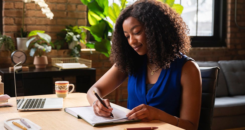 Woman in modern office writing in FOUNDATION planner