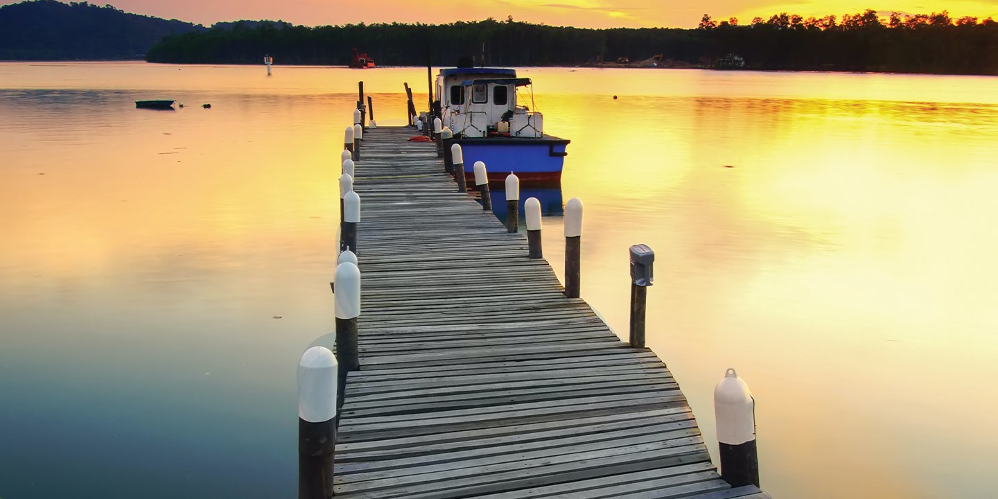 Small boat sitting at the end of a wooden dock